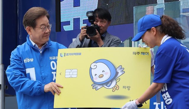 이재명 당시 더불어민주당 대선 후보가 지난달 20일 경기 파주시 금릉역 중앙광장에서 열린 유세에서 지역화폐 모형을 전달받고 있다. 연합뉴스