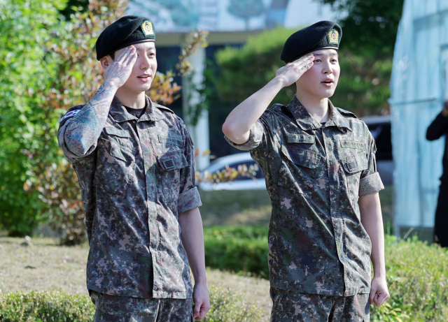 육군 병장으로 만기 전역한 BTS 지민(오른쪽)과 정국이 11일 경기 연천군 연천공설운동장에서 열린 기념행사에서 팬들에게 거수경례로 전역 인사하고 있다. 연천=연합뉴스