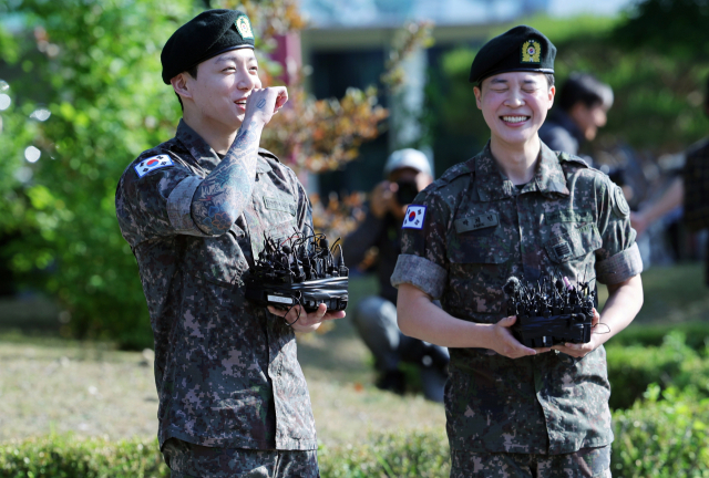 육군 병장으로 만기 전역한 BTS 지민과 정국이 11일 경기 연천군 연천공설운동장에서 열린 기념행사에서 팬들에게 인사하며 웃고 있다. 연천=연합뉴스