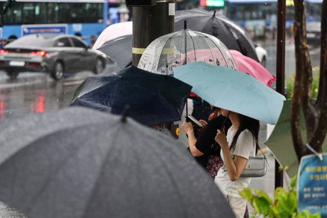 서울 전역에 호우주의보가 내린 20일 서울 종로구 광화문 네거리에서 우산을 쓴 시민들이 신호를 기다리고 있다. 연합뉴스