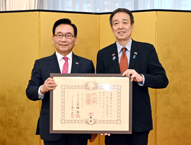김기병(왼쪽) 롯데관광개발 회장이 24일 서울 성북구 주한일본대사관저에서 미즈시마 고이치 주한일본대사로부터 ‘욱일중수장’을 받고 있다. 사진 제공=롯데관광개발