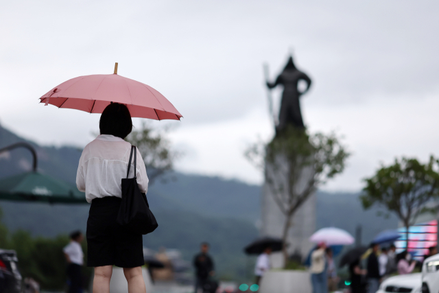 25일 오전 서울 세종로사거리에서 시민들이 우산을 쓴 채 보행 신호를 기다리고 있다. 연합뉴스