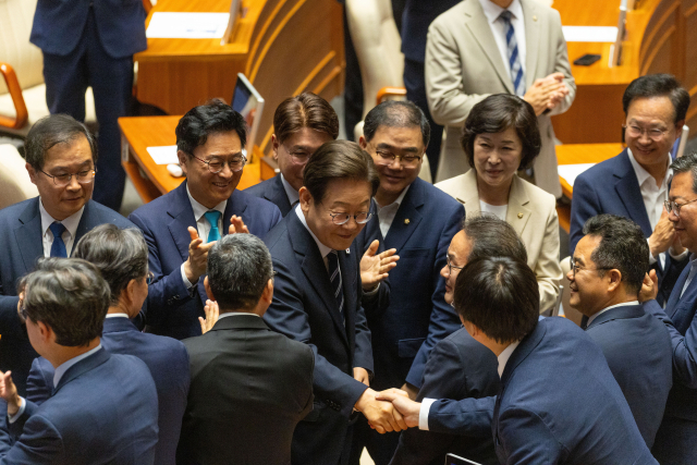 이재명 대통령이 26일 국회 본회의장에서 2025년도 제2회 추가경정예산안에 대한 정부의 시정연설을 하기 위해 본회의장으로 입장하며 더불어민주당 의원들과 인사를 나누고 있다. 2025.6.26/뉴스1