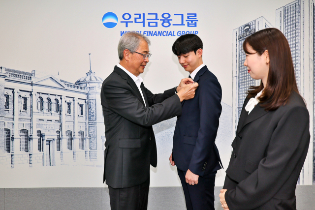 임종룡(왼쪽) 우리금융지주 회장이 1일 그룹의 새 가족이 된 동양·ABL생명 직원에게 디지털 금융을 선도하겠다는 의미가 담긴 새 그룹 보조 휘장을 달아주고 있다. 사진 제공=우리금융그룹