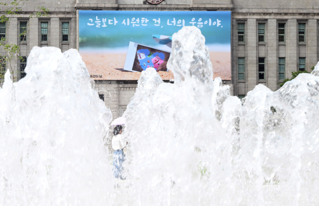 서울 전역에 올해 첫 폭염주의보가 발령된 지난달 30일 시민들이 '그늘보다 시원한 건, 너의 웃음이야'라는 문구로 교체된 서울 중구 서울도서관 꿈새김판 앞을 지나고 있다. 오승현 기자