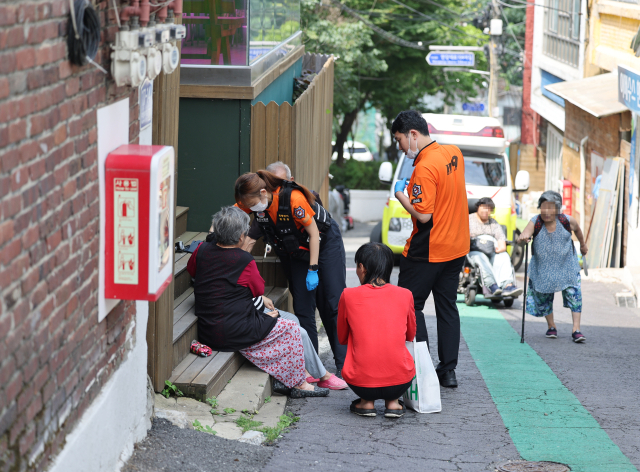기록적인 폭염으로 서울에서 온열질환이 작년보다 3배 이상 발생한 가운데 9일 서울역 앞 쪽방촌 골목에 앉아 대화를 나누던 한 주민이 쓰러지자 119 구급대원들이 출동하고 있다. 연합뉴스
