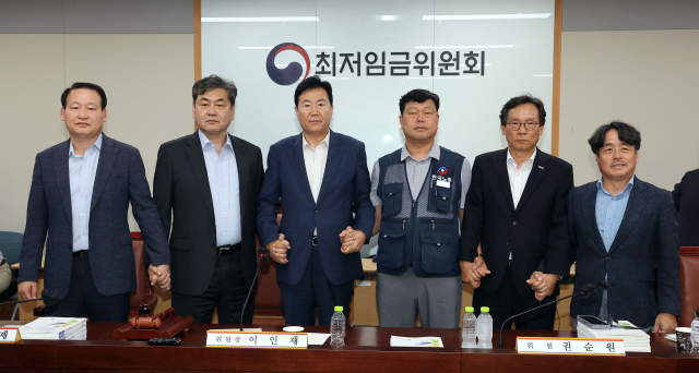 10일 정부세종청사에서 열린 제12차 전원회의에서 내년 최저임금을 시간당 1만320원으로 17년만에 합의로 결정한 공익위원-사용자위원-근로자위원들이 손을 잡고 기념촬영을 하고 있다. 왼쪽부터 하헌제 상임위원, 이인재 위원장, 사용자위원인 류기정 한국경영자총협회 전무, 근로자위원인 류기섭 한국노총 사무총장, 사용자위원인 이명로 중소기업중앙회 인력정책본부장, 공익위원인 권순원 숙명여대 교수. 연합뉴스