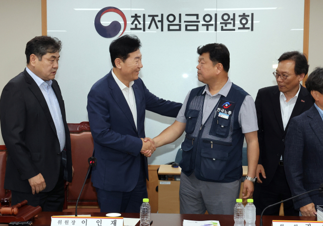 최저임금위원회 사용자위원 운영위원인 류기정(왼쪽) 한국경영자총협회 전무와 근로자위원 운영위원인 류기섭 한국노총 사무총장이 10일 정부세종청사에서 열린 제12차 전원회의에서 내년 최저임금을 시간당 1만320원으로 17년 만에 합의로 결정한 뒤 악수하고 있다. 왼쪽은 이인재 위원장, 오른쪽은 이명로 중소기업중앙회 인력정책본부장. 연합뉴스