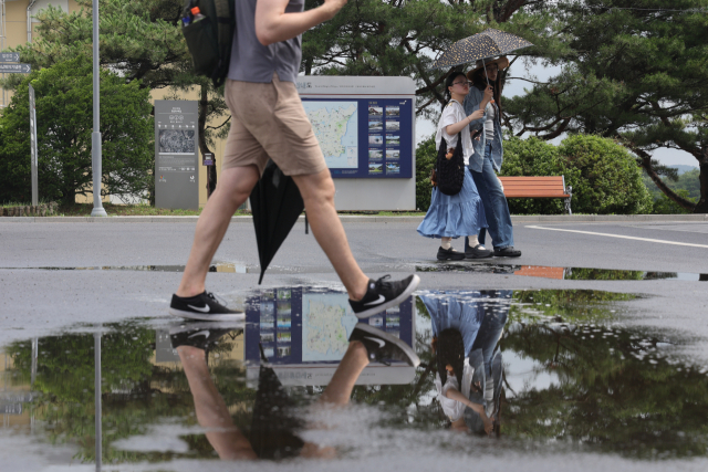 1일 경기도 파주시 임진각에서 관광객들이 양산과 우산을 든 채 장맛비로 젖은 땅을 걷고 있다. 연합뉴스
