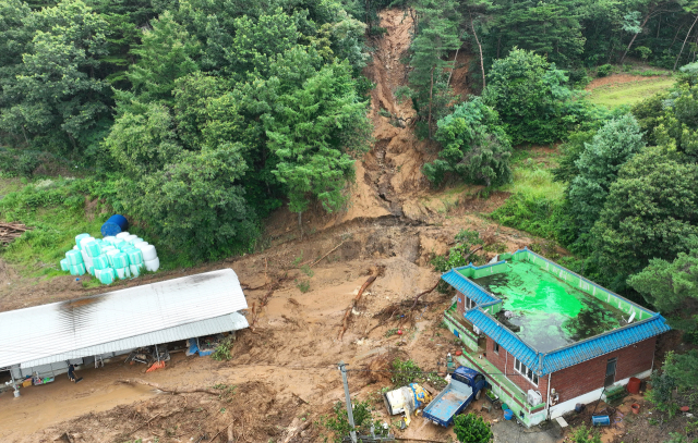 18일 전날 내린 폭우로 산사태가 발생한 충남 예산군 봉산면의 한 마을에서 토사와 나무가 주택과 축사를 덮쳐 처참한 모습을 보이고 있다. 주민은 