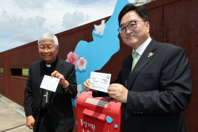 우원식 국회의장과 유흥식 추기경이 23일 경기도 파주 임진각 평화누리공원 통일기원 느린우체통 앞에서 메시지를 적은 엽서를 들어보이고 있다. 연합뉴스