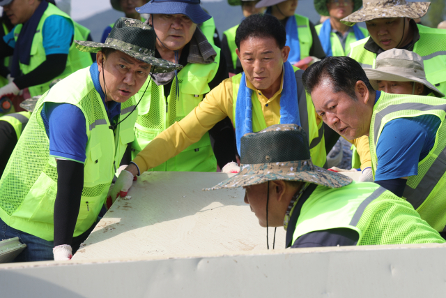 더불어민주당 김병기 당 대표 직무대행 겸 원내대표(왼쪽)가 24일 오전 경기도 가평군 조종면 현리 수해 현장에서 당 대표 선거에 출마한 정청래 의원(오른쪽)과 함께 복구 작업을 돕고 있다. 연합뉴스