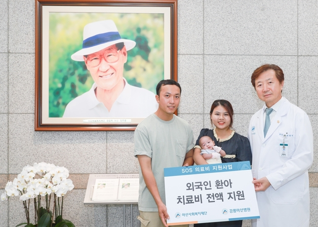유창식(오른쪽) 병원장과 환아의 가족이 고(故) 정주영 아산사회복지재단 설립자의 사진 앞에서 기념 촬영을 하고 있다. 사진 제공=강릉아산병원