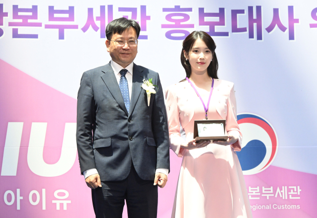 아이유(IU·본명 이지은)가 25일 인천국제공항 제1터미널에서 열린 인천공항본부세관 홍보대사 위촉식에서 김종호 세관장에게 위촉패를 받은 뒤 기념 촬영을 하고 있다. 영종도=오승현 기자 2025.07.25