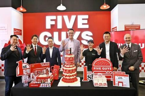 김동선(가운데) 한화갤러리아 전략본부장 부사장과 관계자들이 지난해 6월 26일 오전 서울 서초구 파이브가이즈 강남에서 열린 파이브가이즈 국내 오픈 1주년 기념 행사에서 포즈를 취하고 있다. 연합뉴스