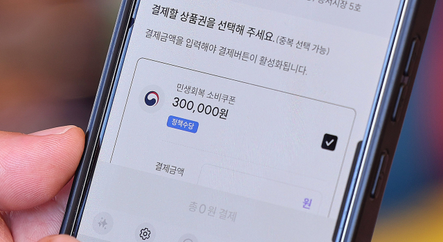 27일 서울 동대문구 청량리종합시장을 찾은 한 시민이 민생회복 소비쿠폰을 사용하고 있다. 뉴스1