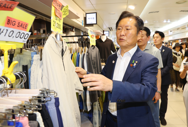 더불어민주당 정청래 당대표 후보가 30일 인천 부평구 부평역지하상가를 찾아 상인들과 인사 하던 중 한 상가에서 아들들의 옷을 고르고 있다. 연합뉴스