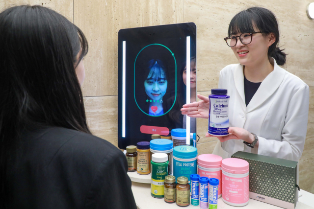 고객이 현대백화점 목동점 네슬레 헬스사이언스 스토어에서 AI기반 첨단 헬스케어 전문 진단 기기 ‘아누라 매직미러(Anura Magic Mirror)’ 앞에 앉아 건강 상태 측정을 하고 있다. 사진 제공=현대백화점그룹