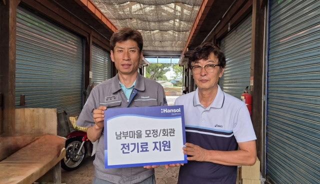 남윤갑(왼쪽) 한솔페이퍼텍 HR지원팀 팀장과 이재천 남부마을 이장이 사업장 인근 담양군 대전면 남부마을에 전기요금 등을 지원식 후 기념 촬영을 하고 있다. 사진 제공=한솔페이퍼텍