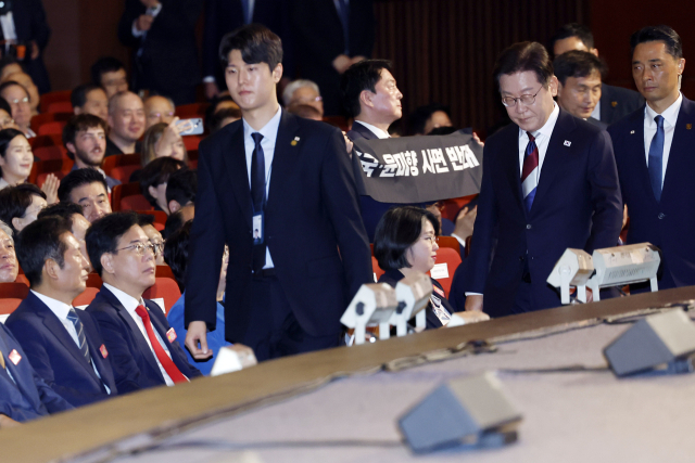 안철수 국민의힘 의원이 15일 서울 세종문화회관에서 열린 80주년 광복절 경축식에서 이재명 대통령이 경축사를 마치고 자리로 향할 때 ‘조국·윤미향 사면 반대’라는 문구가 적힌 펼침막을 들어 보이고 있다. 연합뉴스