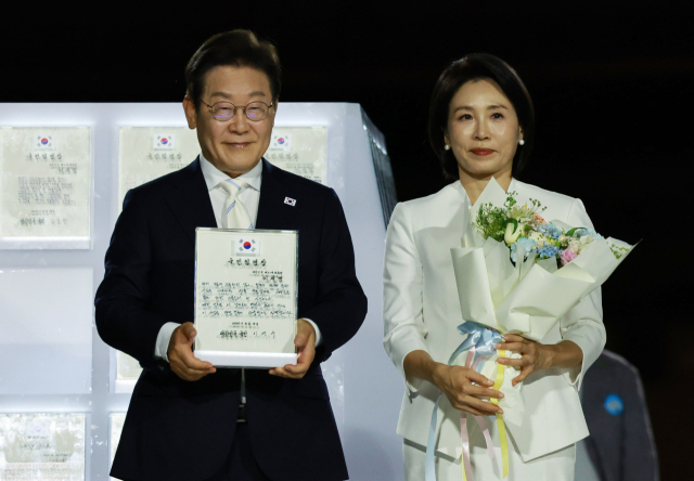 이재명 대통령과 김혜경 여사가 15일 서울 세종대로 광화문광장에서 열린 제21대 대통령 국민임명식 '광복 80년, 국민주권으로 미래를 세우다' 행사에서 국민 대표 80인으로부터 '빛의 임명장'을 받은 뒤 감사 인사를 하고 있다. 연합뉴스
