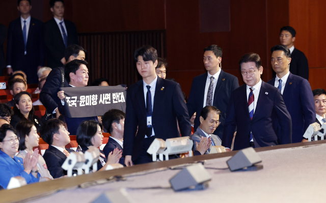안철수 국민의힘 의원이 15일 서울 세종문화회관에서 열린 80주년 광복절 경축식에서 이재명 대통령이 경축사를 마치고 자리로 향할 때 '조국·윤미향 사면 반대'라는 문구가 적힌 펼침막을 들어보이고 있다. 대통령실통신사진기자단