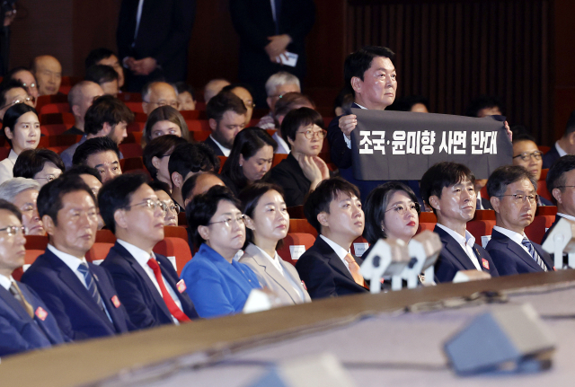 안철수 국민의힘 당 대표 후보가 이달 15일 서울 세종문화회관에서 열린 80주년 광복절 경축식에서 이재명 대통령이 경축사를 마치고 자리로 향할 때 '조국·윤미향 사면 반대'라는 문구가 적힌 펼침막을 들어보이고 있다. 연합뉴스