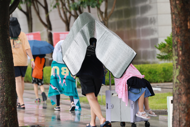 소나기가 내린 서울 광화문광장 인근에서 한 가족이 돗자리로 비를 막으며 이동하고 있다. 연합뉴스