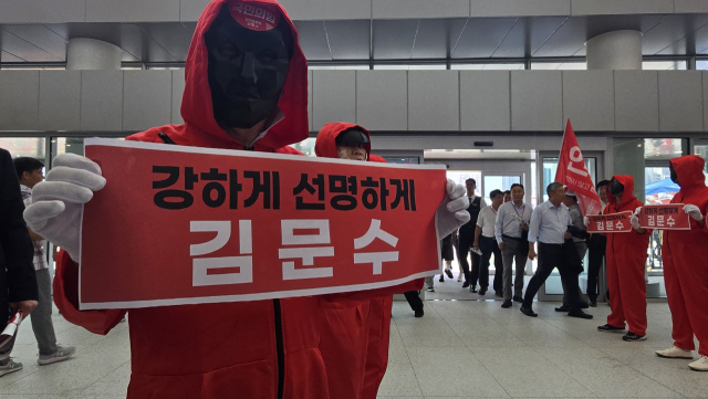 22일 제6차 국민의힘 전당대회가 열린 충북 청주 오스코에서 김문수 당 대표 후보 지지자가 ‘오징어게임’ 복장을 하고 플래카드를 들어 보이고 있다. 청주=이승령 기자
