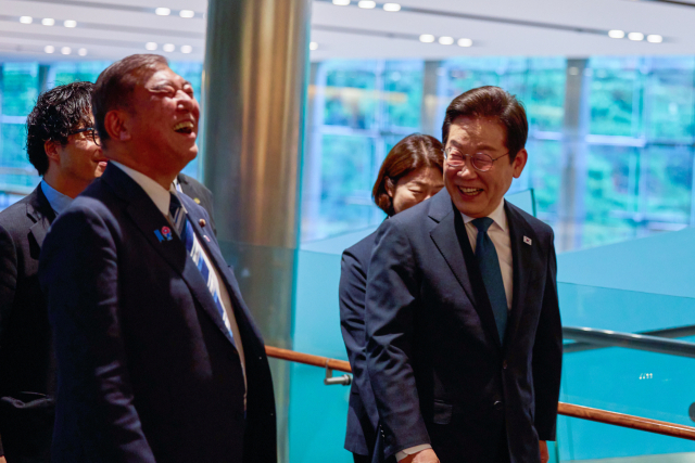 이재명 대통령이 23일 일본 도쿄 총리 관저에 도착해 이시바 시게루 일본 총리와 대화하며 이동하고 있다. 연합뉴스