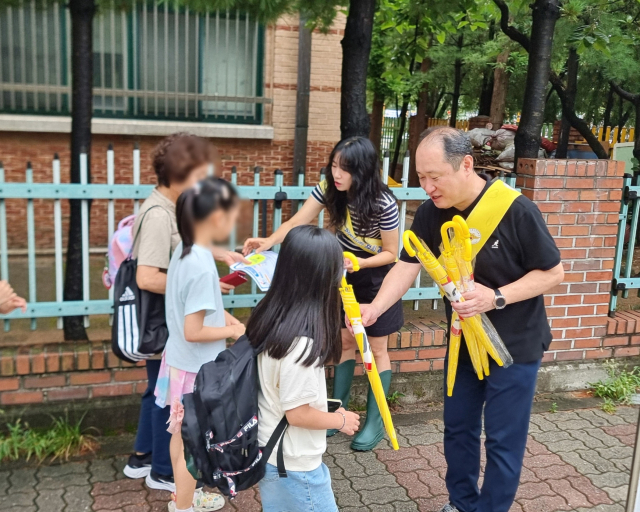 26일 오전 구로구청 직원이 어린이들에게 우산 등의 홍보물을 배부하고 있다. 사진제공=구로구