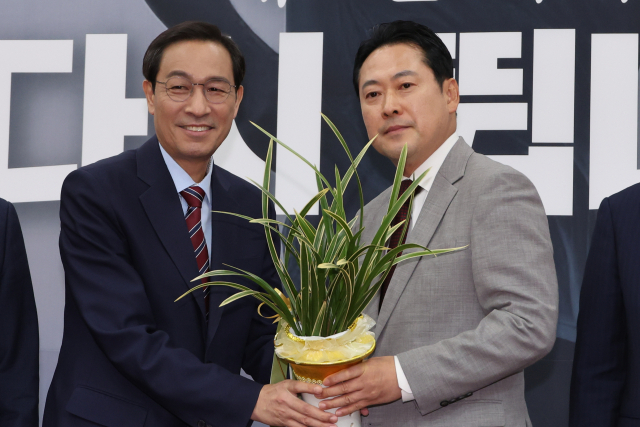 장동혁(오른쪽) 국민의힘 대표가 27일 서울 여의도 국회에서 우상호 대통령실 정무수석으로부터 축하 난을 받고 있다. 우 수석은 이날 이재명 대통령이 조만간 여야 대표에게 한일·한미 정상회담의 성과를 공유하는 자리를 마련할 예정이라고 밝혔다. 연합뉴스