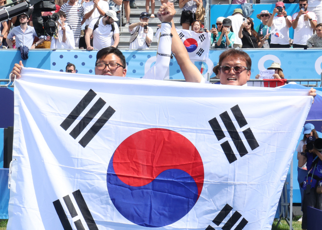 프랑스 파리 레쟁발리드에서 열린 2024 파리올림픽 양궁 남자 개인전 미국의 브레이디 엘리슨과의 결승에서 승리한 한국 김우진이 박성수 감독과 태극기를 들고 관중에게 인사하고 있다. 2024.8.4. 연합뉴스