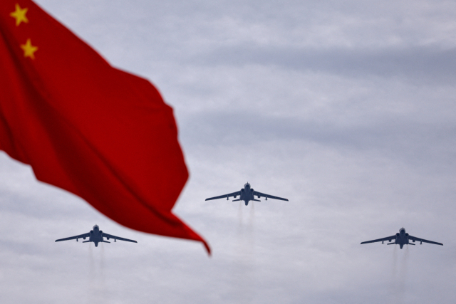시안 H-6N 제트 폭격기가 24일 중국 베이징에서 열린 전승절 80주년 열병식 예행 연습에서 중국 국기 뒤쪽으로 편대비행을 하고 있다. 로이터연합뉴스