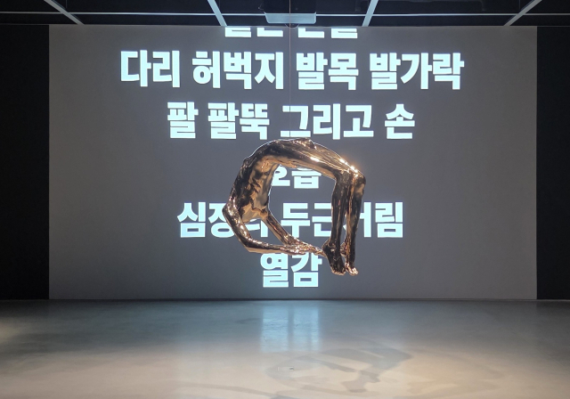 루이스 부르주아의 '히스테리아의 아치(1993)' 뒤로 부르주아의 텍스트에 생명력을 불어넣은 제니 홀저의 라이트 프로젝션이 상영되고 있다. /김경미기자
