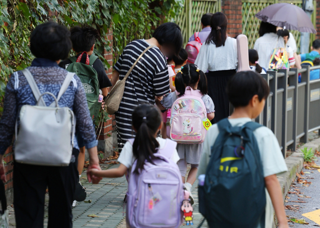 5일 서울 서대문구 한 초등학교에서 학부모들이 자녀 손을 잡고 함께 등교하고 있다. 서대문경찰서는 3일 미성년자 유인 미수 혐의를 받는 3명을 긴급체포했다. 연합뉴스