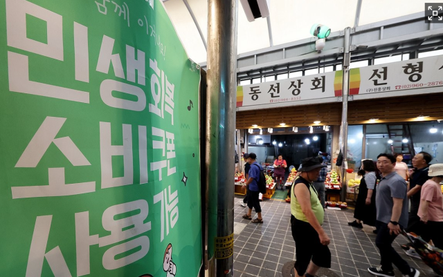 서울의 한 전통시장에 민생회복 소비쿠폰 안내문이 붙여 있다. 연합뉴스