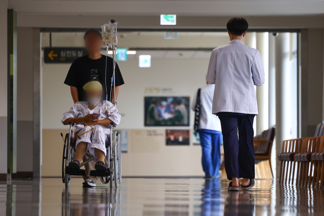 서울 시내 한 대학병원에서 한 의료 관계자가 환자와 보호자 옆으로 이동하고 있다. 연합뉴스