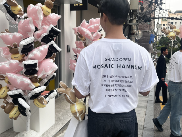 모자이크 한남 앞 거리에서 각 나라별 소개 문구가 적힌 티셔츠를 입은 직원이 오픈 기념 홍보를 하고 있다. 노현영 기자.