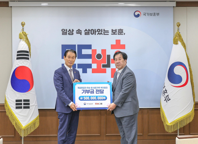 우오현(오른쪽) SM그룹 회장과 권오을 국가보훈부 장관이 13일 정부세종청사에서 열린 국가보훈부의 전 국민 보훈 기부 프로젝트 ‘모두의 보훈 드림’ 후원금 전달식에서 기념 촬영을 하고 있다. 사진 제공=SM그룹