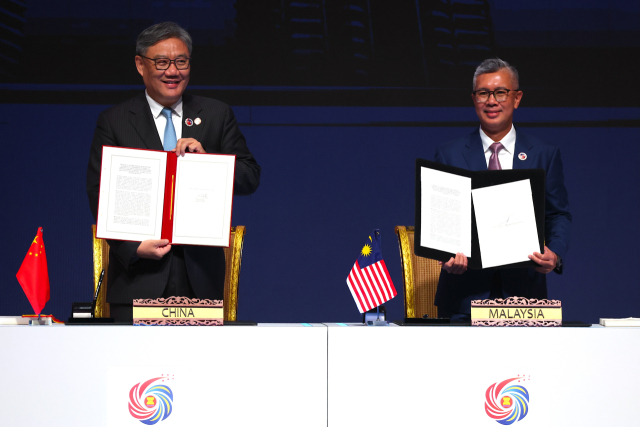 28일(현지시간) 말레이시아 쿠알라룸푸르에서 왕원타오(왼쪽) 중국 상무부장(장관)과 틍쿠 자프룰 아지즈 말레이시아 투자통상산업부 장관이 아세안-중국 자유무역협정(FTA) '버전 3.0' 확대 개정안에 서명하고 들어보이고 있다. EPA연합뉴스