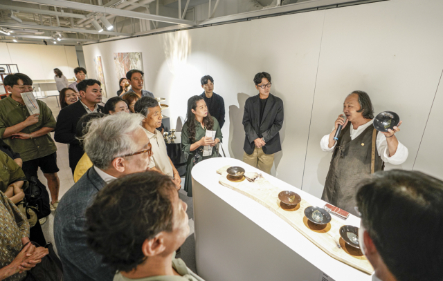 김대철 명인이 포항문화예술팩토리 아트갤러리에서 열리고 있는 'K-헤리티지 아트전-이음의 변주'에서 공개 중인 자신의 목엽천목을 들고 관람객들에 설명하고 있다. 사진 제공=세이버스코리아