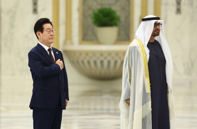 이재명 대통령이 18일(현지 시간) 아랍에미리트(UAE) 아부다비 대통령궁에서 열린 국빈 방문 공식 환영식에서 국기에 경례하고 하고 있다. 오른쪽은 무함마드 빈 자이드 알나하얀 UAE 대통령. 연합뉴스