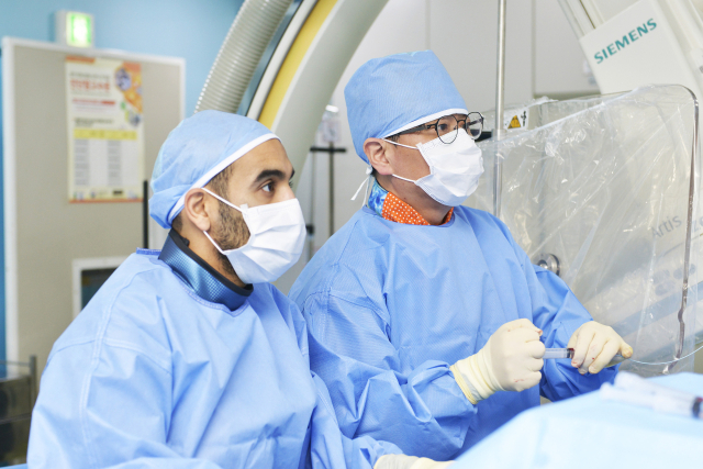 사우디아라비아에서 연수를 받으러 온 킹파이살전문병원 소속 투르키 파르한 알파르한(왼쪽·Turki Farhan S. Alfarhan)씨가 이상환 양지병원 영상의학과 전문의의 미세동맥색전술(TAME) 시행 과정을 지켜보고 있다. 사진 제공=에이치플러스 양지병원