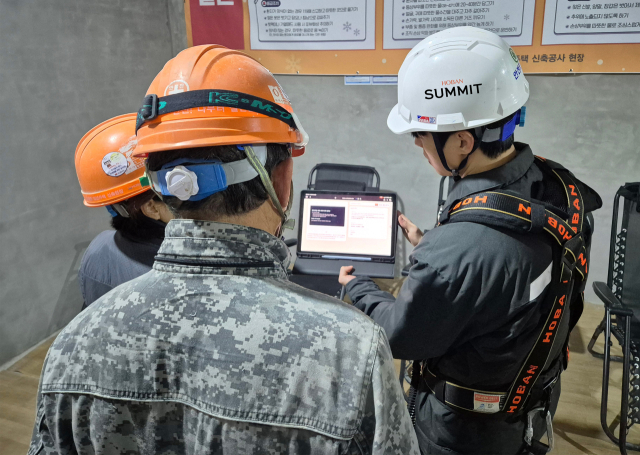 호반건설 직원이 건설 현장에서 AI 동시번역 플랫폼 ‘호반커넥트’를 활용해 근로자들과 대화하고 있다. 사진 제공=호반건설