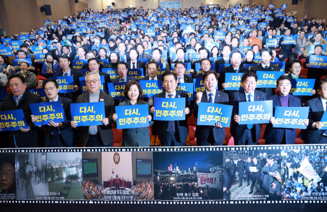 정청래(앞줄 왼쪽 다섯 번째) 더불어민주당 대표를 비롯한 의원들이 3일 국회 의원회관에서 '행동하는 K민주주의' 특별 좌담회에 참석해 손팻말을 들고 구호를 외치고 있다. 연합뉴스